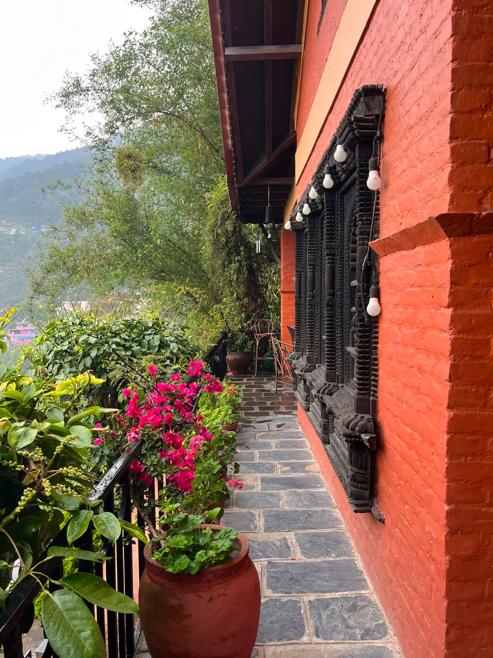 Stone balcony walkway with bougainvillea and carved Newari windows